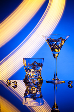 Two glasses a cocktail Martini whisky ice, against the blue background of beautiful light effects.の写真素材