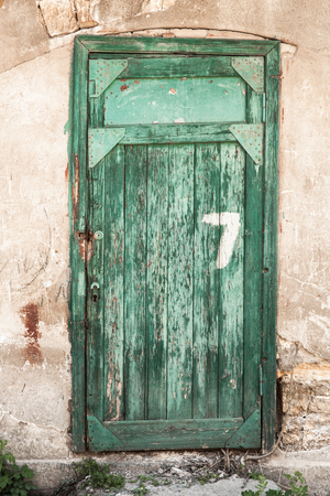 
Old green wooden doors with the number seven, a dilapidated wall.の写真素材