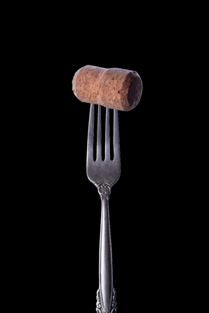 Vintage silver fork with wine stopper on black background.
