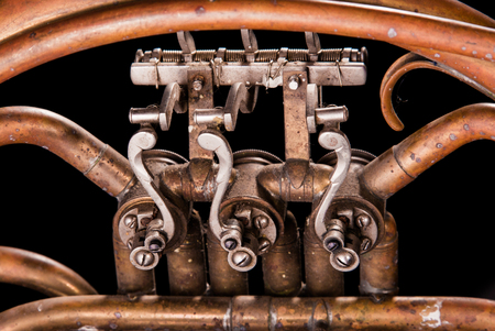 Vintage bronze pipes, valve, key mechanical elements french horn on black isolated background. Good pattern, prompt music instrument.の写真素材