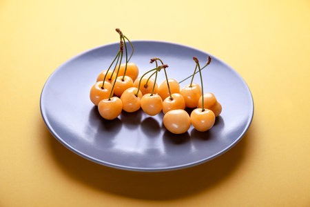 Berries yellow cherry on  blue plate on  yellow background,  natural product, a good idea for store.の写真素材