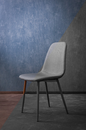 Grey modern textile chair with wood on a background of a wall. Good concept for hotel.の写真素材