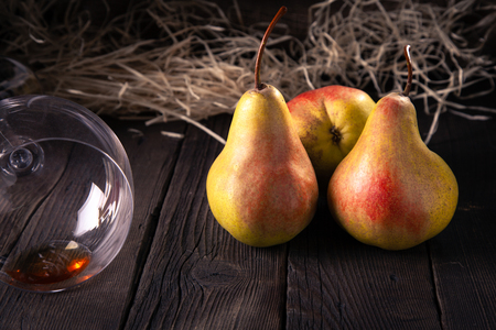 Pears on a wooden table in the village and a glass with the rest of the alcoholic drink is a good concept for healthy food.の写真素材