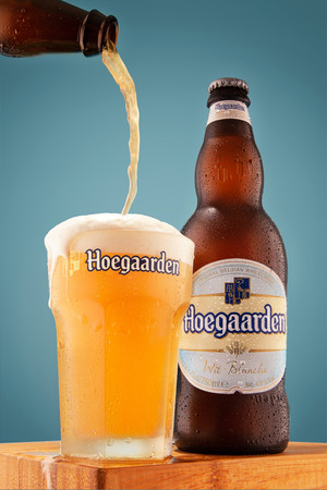 Beer Bottle Hoegaarden Wit Blanche and the original glass was filled with beer, 
on a heavenly background is on a wooden table, very beautiful foam.のeditorial素材