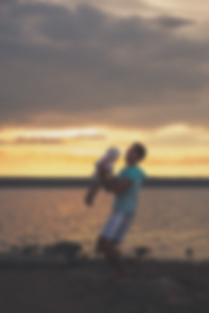 Blurred - Young father and his daughter at sunset on the lake. Very emotional moment.の写真素材