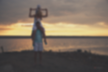 Blurred - young family father mother and daughter at sunset on the lake. Very emotional moment.の写真素材