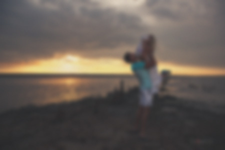 Blurred - young family father mother and daughter at sunset on the lake. Very emotional moment.の写真素材
