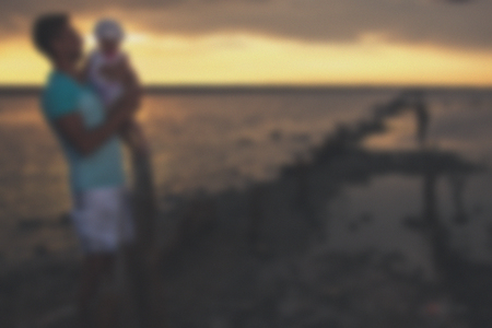 Blurred - Young father and his daughter at sunset on the lake. Very emotional moment.の写真素材