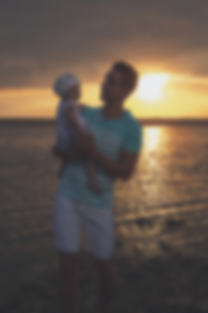 Blurred - Young father and his daughter at sunset on the lake. Very emotional moment.の写真素材