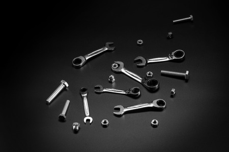 Nuts, bolts, wrench, ratchet on a dark background. Tools for fastening bolted connections.