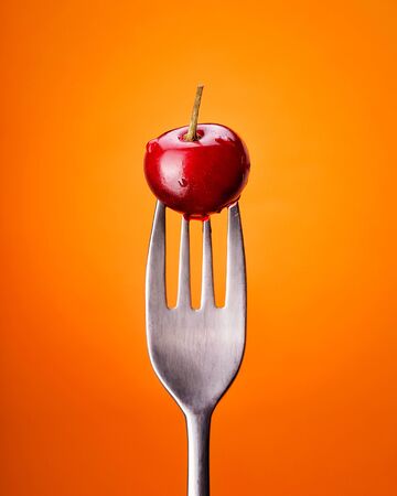 Natural cherry on a fork with water drops. Oreginal concept. Front view.の写真素材