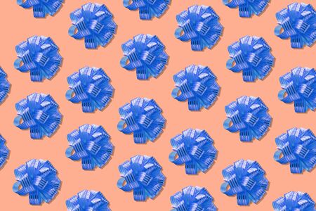Gift bow pattern, on a colored background in pastel color. Minimal festive concept. From top view.
