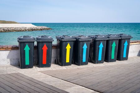 Litter bins with multi-colored arrows near the sea against the blue sky on the waterfront. The...