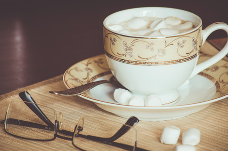 A cup of coffee, marshmallows and glasses on the bamboo napkinの写真素材