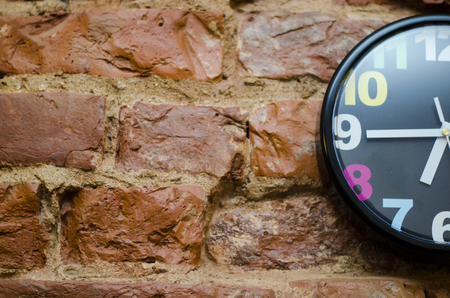 A half of a colored wall clock on a brick wall. Front viewの写真素材