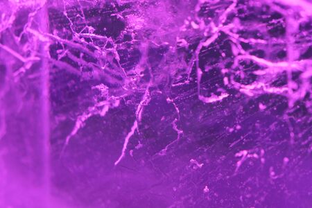 Abstract background of illuminated purple ice texture with cracks and bubbles insideの写真素材