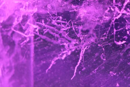 Abstract background of illuminated purple ice texture with cracks and bubbles insideの写真素材