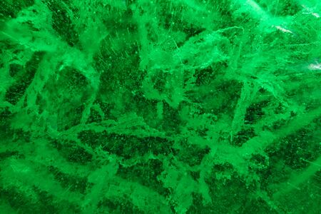 Abstract background of illuminated green ice texture with cracks and bubbles insideの写真素材