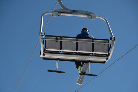 Ski lift with skiers and snowboarders on blue sky