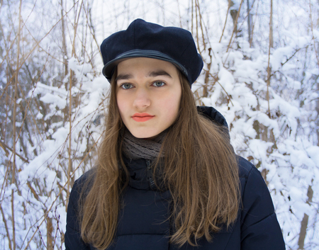 Winter portrait of serious cute beautiful attractive young teen girl with long blonde hair with gray...