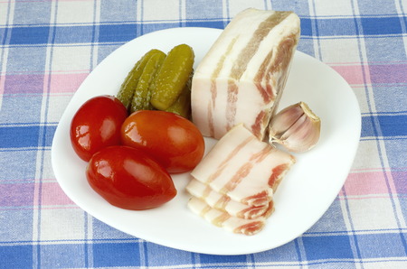 Salty bacon with garlic and homemade pickles on the plateの写真素材