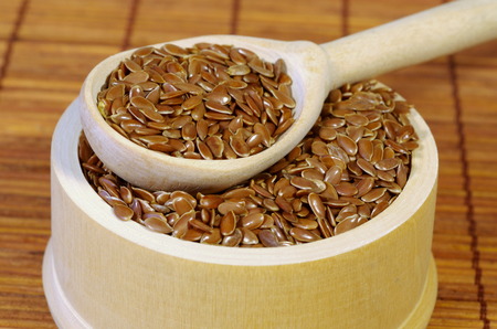 Flax seeds in wooden bowl with spoon closeupの写真素材