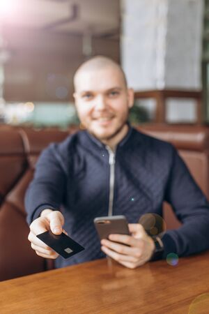 Young handsome man enters credit card information into the phoneの写真素材