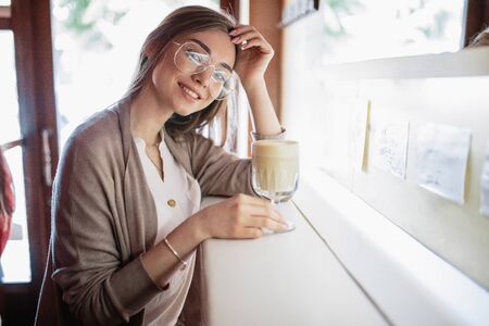 beautiful blond girl near the cafe with a cup of coffeeの写真素材