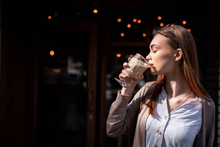 beautiful blond girl near the cafe with a cup of coffeeの写真素材