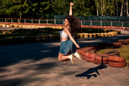 Beautiful young woman in denim overalls on the go-kart track