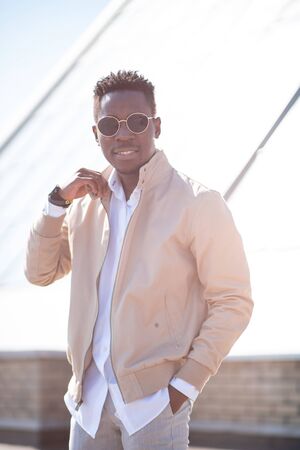 Handsome black young man in a jacket and white shirt on the street. Businessman