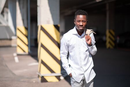 Handsome black young man in a jacket and white shirt on the street. Businessman