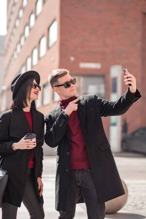 young beautiful woman and young handsome man take a selfie among the cityの写真素材