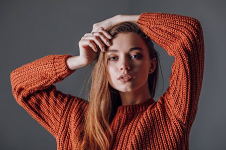 Young attractive woman in a red sweater on a gray background. Emotionsの写真素材