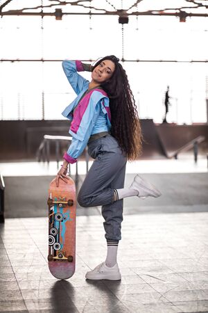 beautiful curly black girl with a skateboard. Skate park