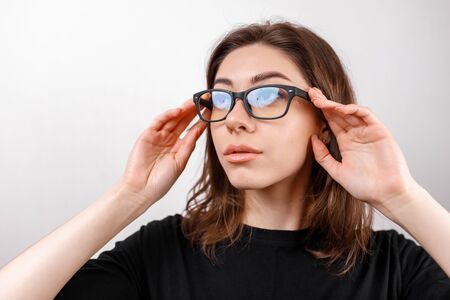beautiful young woman on a white background looks away with glasses and a black T-shirt. copyspace. isolatedの写真素材