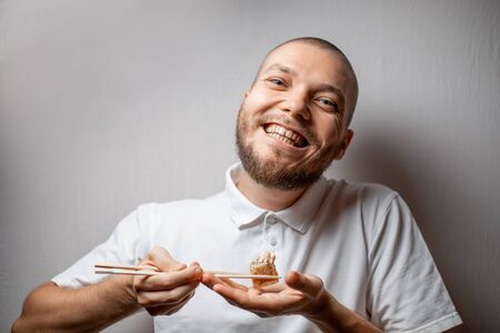 Funny picture of young man is holding sushi rolls on white background. copyspaseの写真素材
