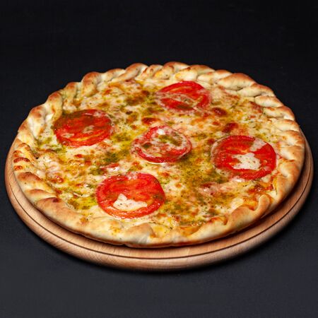 Delicious pizza served on a wooden plate isolated on blackの写真素材