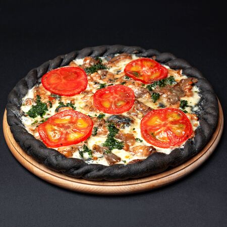 Delicious pizza served on a wooden plate isolated on blackの写真素材