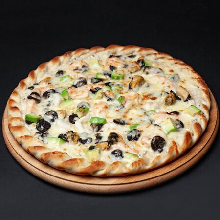 Delicious vegetarian pizza served on a wooden plate isolated on blackの写真素材
