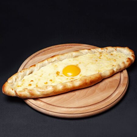 Delicious pizza served on a wooden plate isolated on blackの写真素材