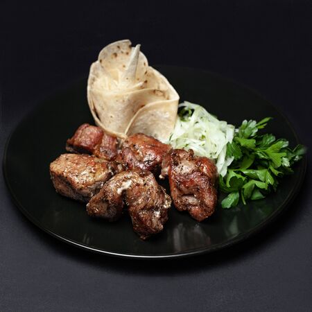 hot skewers on a black plate with pita bread and herbs on a black backgroundの写真素材