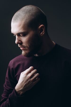close-up portrait of a serious young man looking away on a gray background. bald with a beard.の写真素材