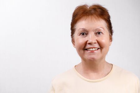 Senior woman on a white background in a light t-shirt. Emotions