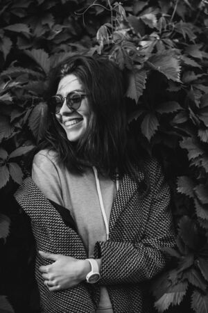 beautiful happy young woman in a sweatshirt on a background of grape leavesの写真素材