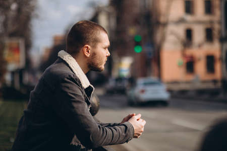 a short-haired man is thoughtful and stands near the road. looks into the distance. expectationの写真素材