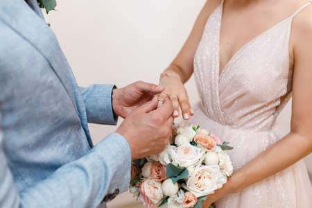 close-up of the groom puts the wedding ring on the finger of the bride at the ceremony.