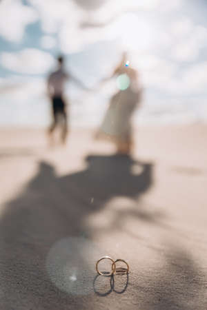the wedding couple goes into the distance against the backdrop of the desert. rings close-up in the foreground.の写真素材