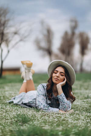 beautiful young woman in a hat and a blue dress lies on a field of wildflowers. Spring.の写真素材