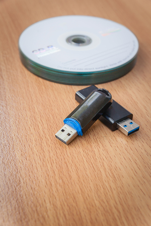 USB flash drives and stacked CDs isolate on wooden background.の写真素材